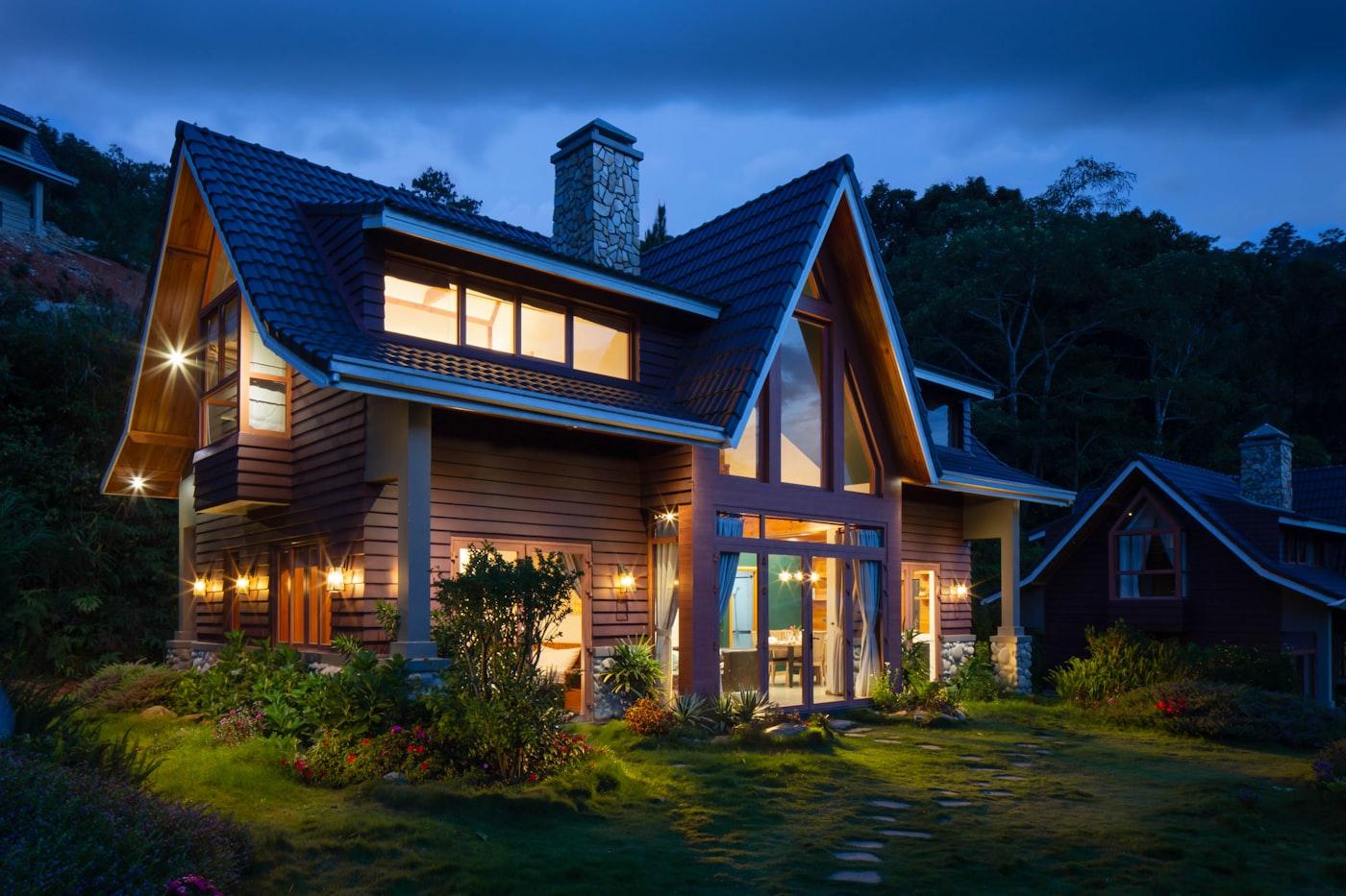 A modern two-story home glowing warmly at dusk